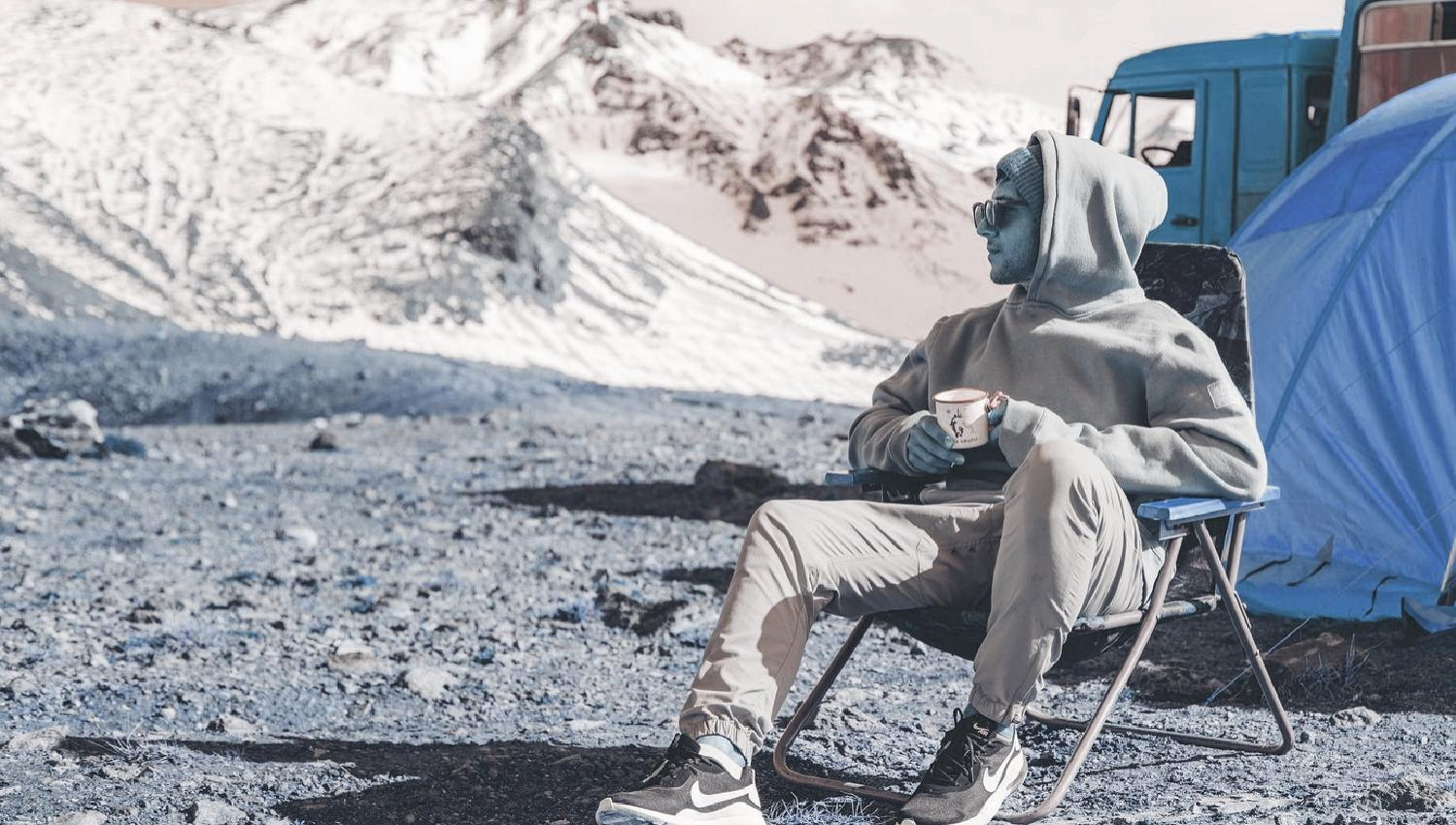 Alpine camp scene with person resting near tent in cold terrain