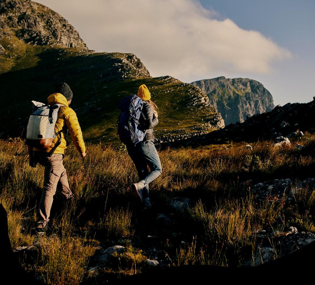 Hikers carrying outdoor backpacks in mountain terrain